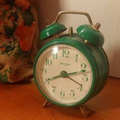 a green alarm clock sitting on top of a wooden table