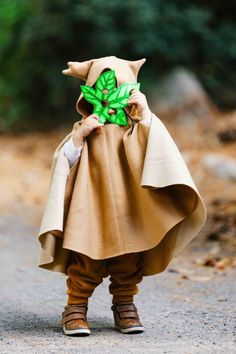 a little boy dressed in a costume with leaves on it's head and hands