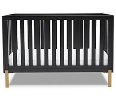 a black crib with white sheets and wood trim on the bottom, in front of a white background