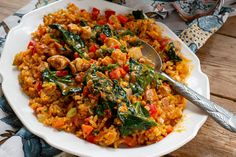 a white plate topped with rice covered in meat and veggies next to a spoon