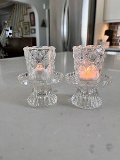 two clear glass candlesticks sitting on top of a white counter in a kitchen