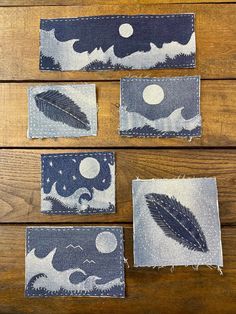 four pieces of fabric with leaves and moon on them sitting on top of a wooden table