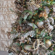 a christmas tree decorated with silver and gold baubles, pine cones, evergreens, ornaments and ribbons