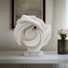 a white sculpture sitting on top of a table next to a vase filled with flowers