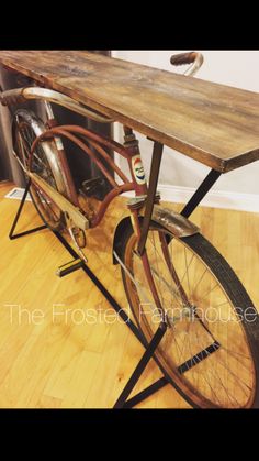 an old bicycle is sitting on the floor next to a wooden table with metal legs