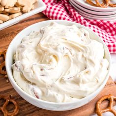 a bowl filled with whipped cream next to pretzels