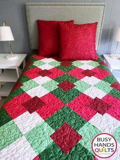 a red and green quilted bed with two lamps on either side of the headboard