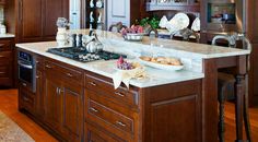 a large kitchen with wooden cabinets and marble counter tops, along with an island in the middle