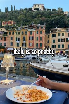 someone is sitting at a table with a plate of food in front of them and the words italy is so pretty