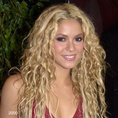 a blonde woman with long curly hair wearing a red dress and smiling at the camera