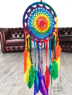 a multicolored dream catcher sitting on top of a wooden floor next to a couch