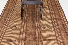 a chair sitting on top of a brown rug next to a wooden table with two chairs