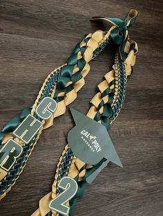 two green and gold braided lanyards on a wooden table with a name tag