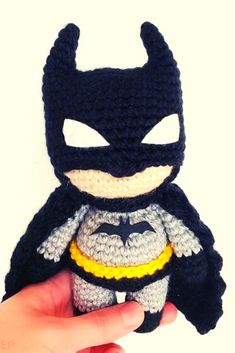 a hand holding a crocheted batman doll