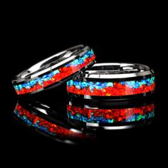 two rings with red, blue and green glitter inlays on black background photo