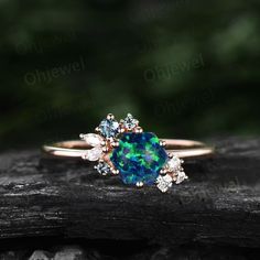 an opal and diamond ring sitting on top of a piece of wood