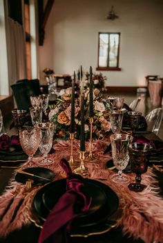 the table is set with black plates and pink napkins