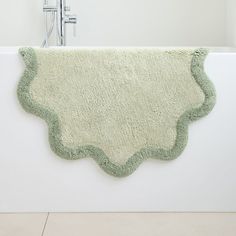 a white bath tub with a green rug on it