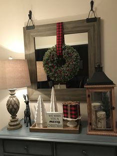 a christmas wreath is hanging on the wall above a dresser with other items and decorations