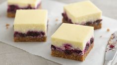 four pieces of cheesecake sitting on top of a white napkin next to blueberries