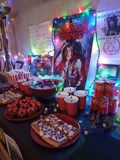 a table topped with lots of desserts and drinks next to a poster on the wall