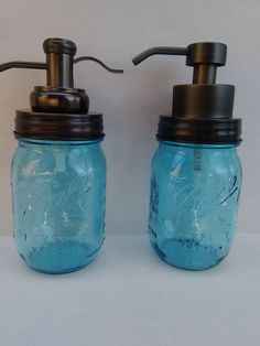 two blue mason jars with soap dispensers on the top one has a metal faucet