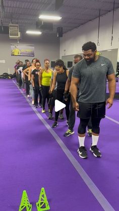 a group of people standing on top of a purple floor next to green traffic cones