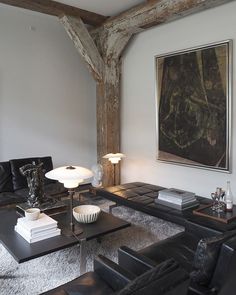 a living room with black leather furniture and a painting on the wall above it's fireplace