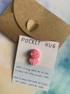 a pink octopus brooch sitting on top of a piece of paper next to a brown envelope