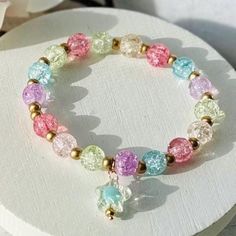 a bracelet with multicolored glass beads and gold accents on top of a white plate