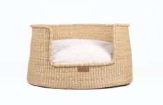 a cat bed made out of woven material with a white fur pillow in the middle