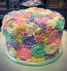 a multicolored cake with icing flowers on the top and bottom is sitting on a table