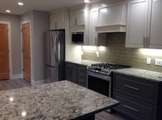 an empty kitchen with granite counter tops and stainless steel appliances in the middle of it