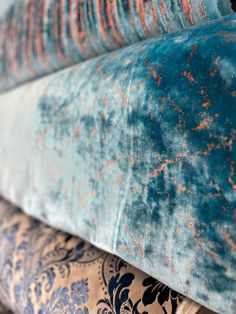 blue and orange velvet pillows stacked on top of each other in different sizes, colors and patterns