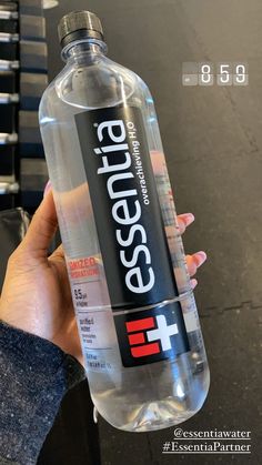 a person holding a bottle of water in their left hand with the words essential on it