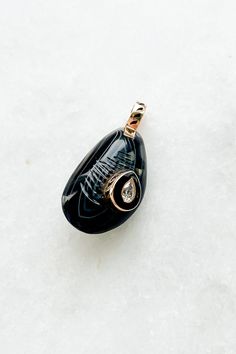 Agate Mussel with Diamond Charm from Dezso by Sara Beltran Hand-carved line agate in the shape of a mussel shell Raised center diamond set in black enamel and 18K gold 18k gold bale with black fin enamel Charm measures approximately 1" length (including bale) x 0.3" width Hand-carved in Jaipur, India Elegant Carved Agate Jewelry, Black Oval Agate Jewelry, Black Intaglio Jewelry As A Gift, Mussel Shell, Diamond Charm, Enamel Charms, Jaipur India, Diamond Set, Black Enamel