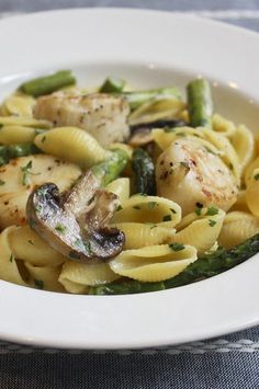 pasta with chicken, asparagus and mushrooms in a white bowl on a table