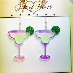 two margaritas with green garnish and lime slices on them are hanging from earrings