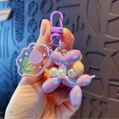 a hand holding a purple flower shaped keychain