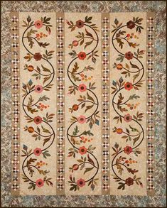 a quilted wall hanging with flowers and leaves on the front, along with an ornate border