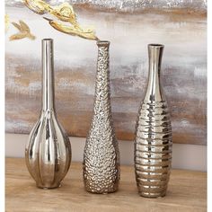 three silver vases sitting on top of a wooden table