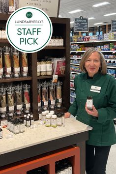 a woman standing in front of a store counter with jars and spices on display behind her