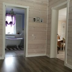 an open door leading to a bathroom with a bathtub and wooden walls in the background