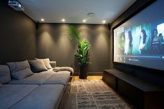 a living room with couches and a flat screen tv on the wall in front of it