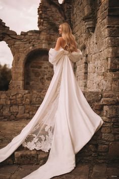 a woman in a white wedding dress standing on some steps with her back to the camera