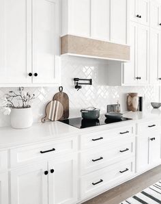 a kitchen with white cabinets and black counter tops, including a range hood over the stove