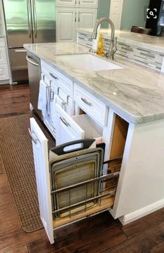 an open dishwasher sitting in the middle of a kitchen counter next to a sink