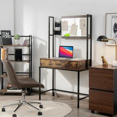 a computer desk with a laptop on top of it next to a chair and bookshelf