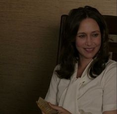 a woman sitting in a chair holding a piece of bread and smiling at the camera