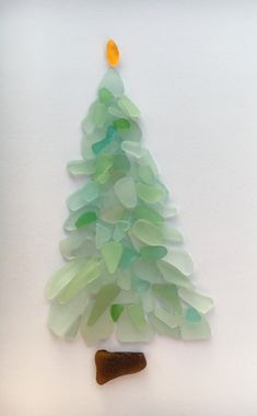 a christmas tree made out of sea glass on a white surface with a dog toy